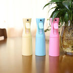 Trois vaporisateurs brumisateurs 200ml pour terrarium, coloris jaune, bleu et rose, posés sur une table à côté d'une plante