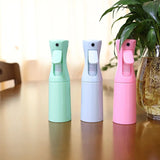 Trois vaporisateurs brumisateurs 200ml pour terrarium, coloris vert menthe, gris et rose, posés sur une table à côté d'une plante