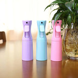 Trois vaporisateurs brumisateurs 200ml pour terrarium, coloris violet, bleu et rose, posés sur une table à côté d'une plante