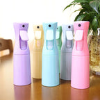 Cinq vaporisateurs brumisateurs 200ml pour terrarium, coloris violet, jaune, bleu, gris et rose, posés sur une table à côté d'une plante